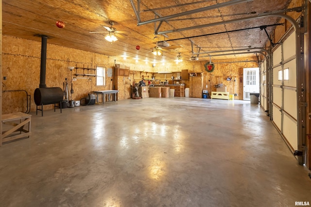 garage with a ceiling fan, heating fuel, a wood stove, and a garage door opener