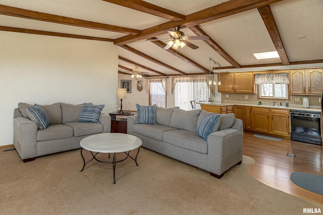 living room featuring vaulted ceiling with skylight, a textured ceiling, light wood-type flooring, and ceiling fan