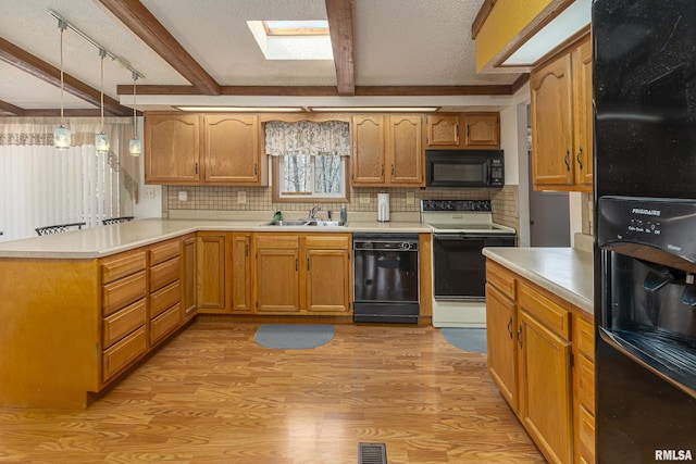 kitchen with beam ceiling, a peninsula, a sink, black appliances, and light wood-type flooring