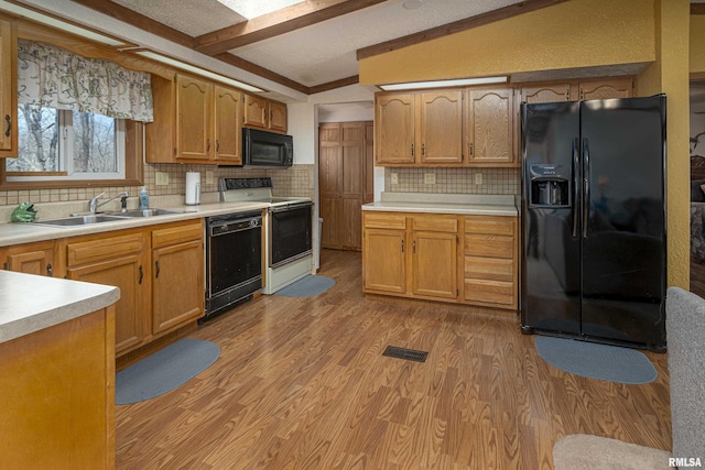 kitchen with visible vents, light wood-type flooring, light countertops, black appliances, and a sink