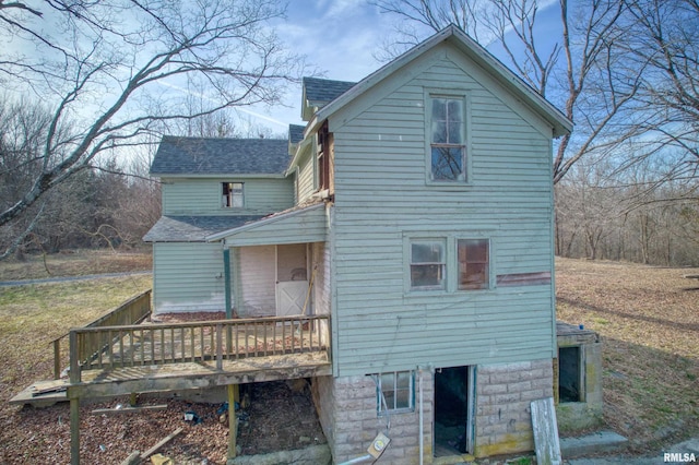 rear view of property featuring roof with shingles, a deck, and a chimney