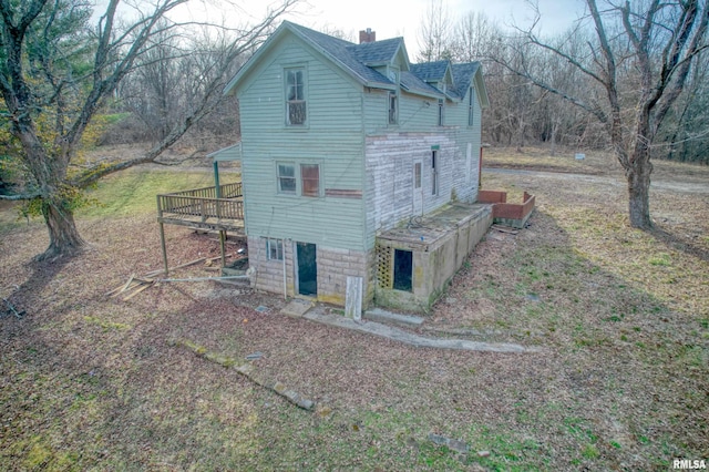 view of side of home with a shingled roof, a wooden deck, and a chimney