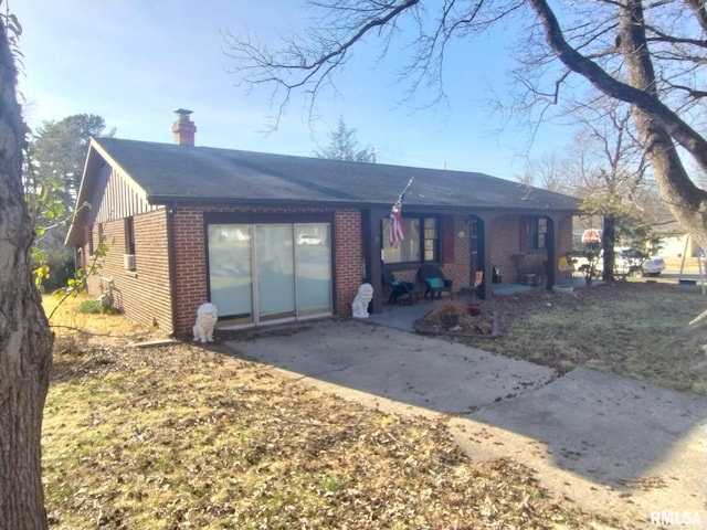 single story home featuring brick siding, driveway, and a chimney