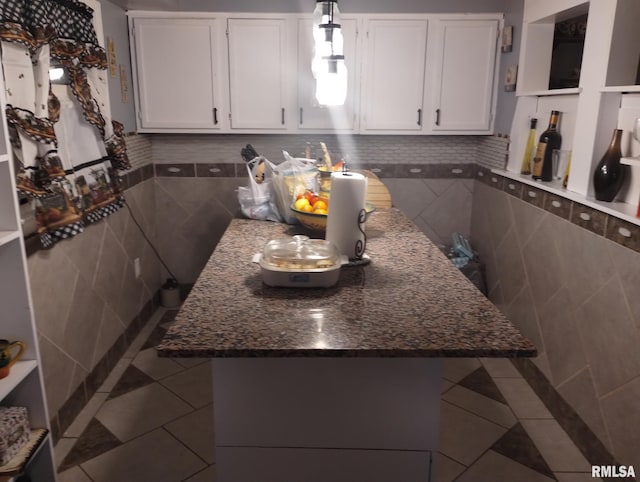 kitchen with tile patterned floors, tile walls, and white cabinetry