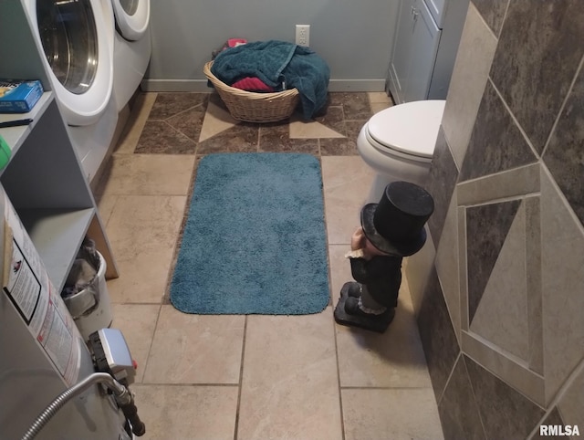 bathroom with baseboards, toilet, and independent washer and dryer