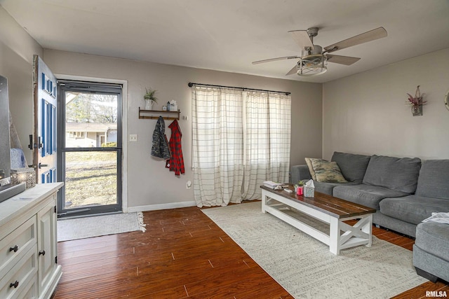 living area with baseboards, a ceiling fan, and wood finished floors