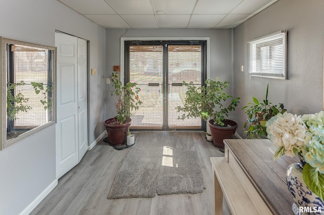 interior space with a paneled ceiling, a healthy amount of sunlight, and wood finished floors