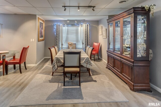 dining area featuring light wood finished floors, track lighting, and baseboards