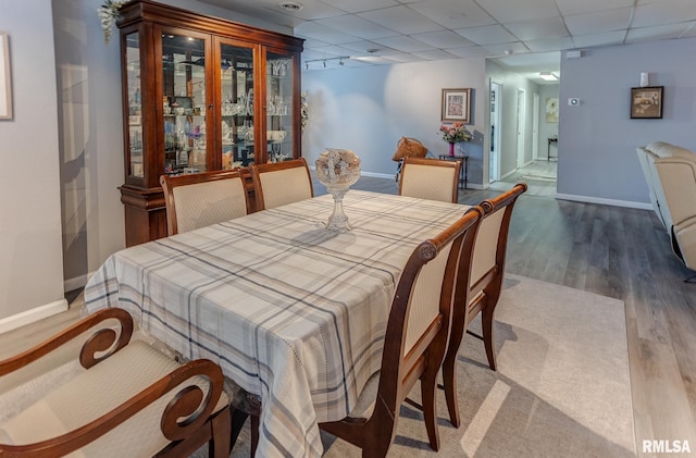 dining area with wood finished floors, a paneled ceiling, and baseboards