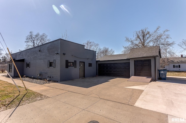 view of property exterior featuring a detached garage, roof with shingles, and concrete block siding