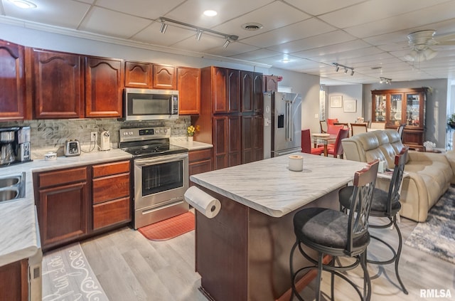 kitchen featuring a kitchen breakfast bar, tasteful backsplash, open floor plan, stainless steel appliances, and light countertops