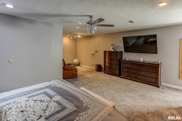 carpeted bedroom with visible vents, baseboards, a textured ceiling, and ceiling fan