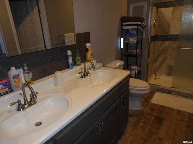 bathroom with a sink, backsplash, toilet, and a shower stall