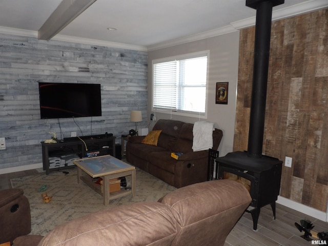 living room with beamed ceiling, ornamental molding, wood finished floors, baseboards, and a wood stove