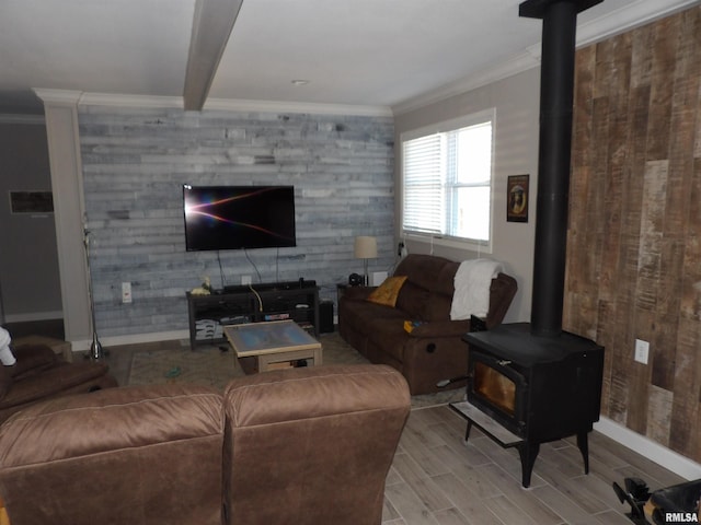 living area featuring crown molding, baseboards, beam ceiling, a wood stove, and wood finished floors