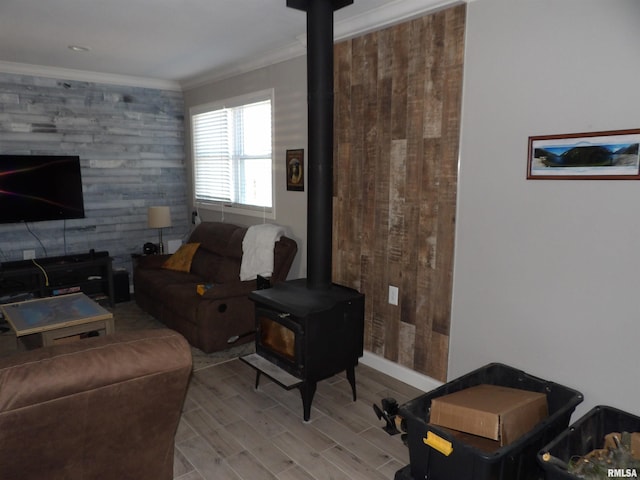 living area with crown molding, a wood stove, wood finished floors, and baseboards