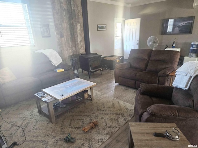 living room with ornamental molding, a wood stove, and wood finished floors