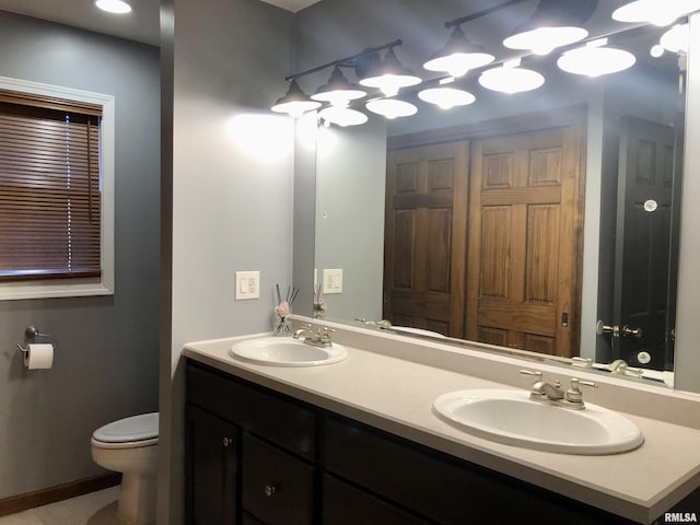 full bathroom featuring a sink, toilet, and double vanity