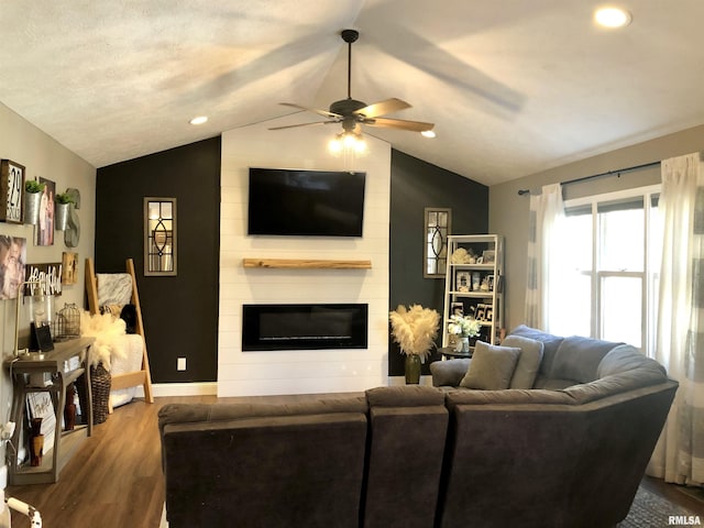 living area featuring ceiling fan, baseboards, lofted ceiling, a fireplace, and wood finished floors