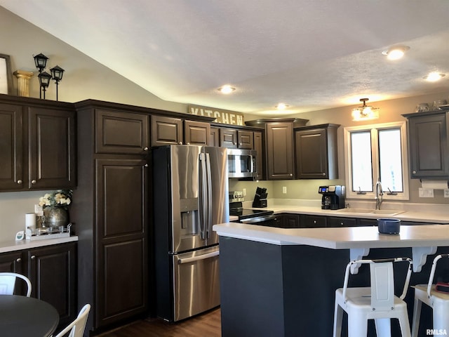 kitchen with a sink, a kitchen bar, appliances with stainless steel finishes, and light countertops