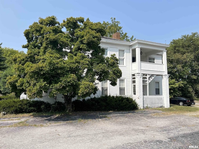 greek revival inspired property with a chimney and a balcony