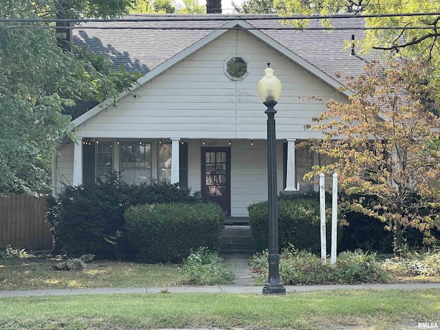 view of front facade featuring fence, a chimney, and a shingled roof