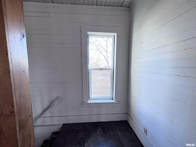 empty room with wooden walls and dark wood-style flooring