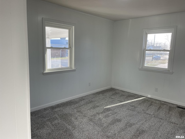 carpeted spare room featuring visible vents, a healthy amount of sunlight, and baseboards