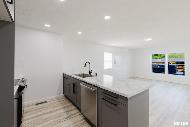 kitchen with a sink, light wood-type flooring, stainless steel appliances, a peninsula, and visible vents