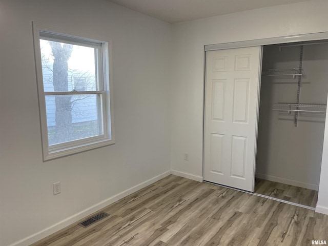 unfurnished bedroom featuring a closet, visible vents, light wood-type flooring, and baseboards