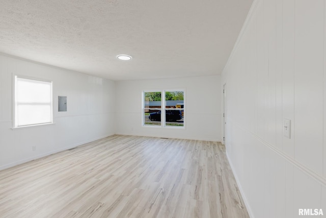 empty room with baseboards, wood finished floors, electric panel, and a textured ceiling