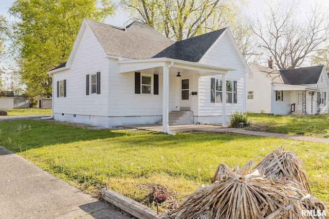 view of front of home with a front lawn, roof with shingles, and entry steps