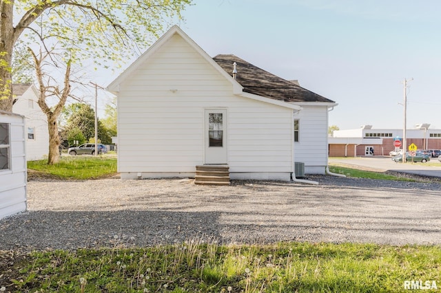 back of property with a shingled roof and entry steps