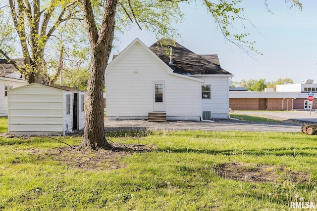 back of property featuring a shingled roof, a storage shed, entry steps, cooling unit, and an outdoor structure