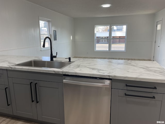 kitchen with dishwasher, light stone counters, gray cabinets, and a sink