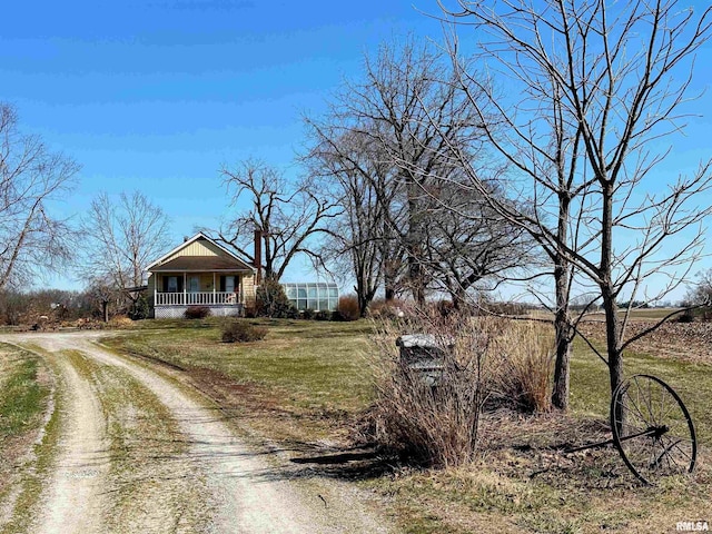 view of front of house with a porch, a front yard, and dirt driveway