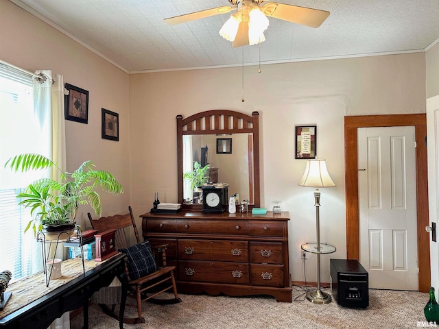 sitting room with a wealth of natural light, carpet floors, ornamental molding, and a ceiling fan