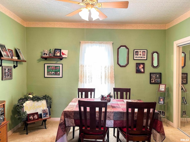 dining room featuring baseboards, light colored carpet, ceiling fan, and a textured ceiling