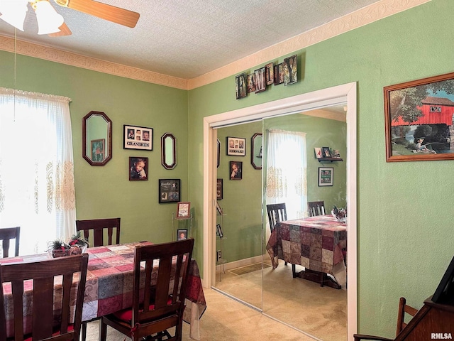 dining space featuring light carpet, plenty of natural light, a textured ceiling, and ceiling fan