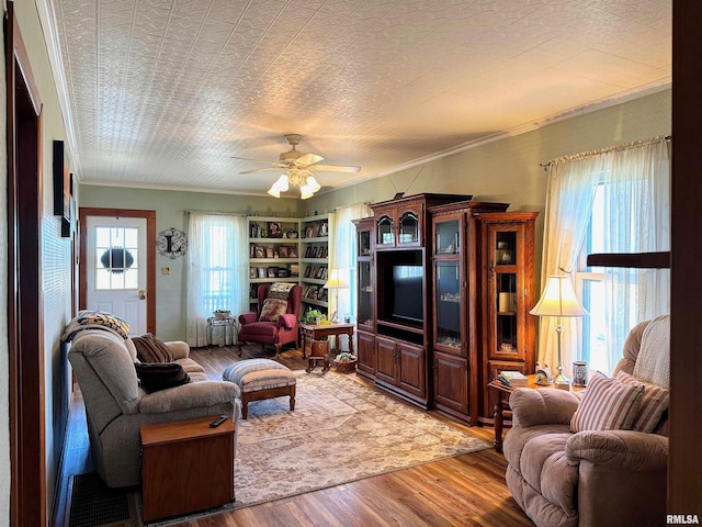 living room with a wealth of natural light, ceiling fan, crown molding, and light wood finished floors