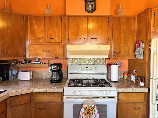 kitchen featuring white appliances, brown cabinets, and under cabinet range hood