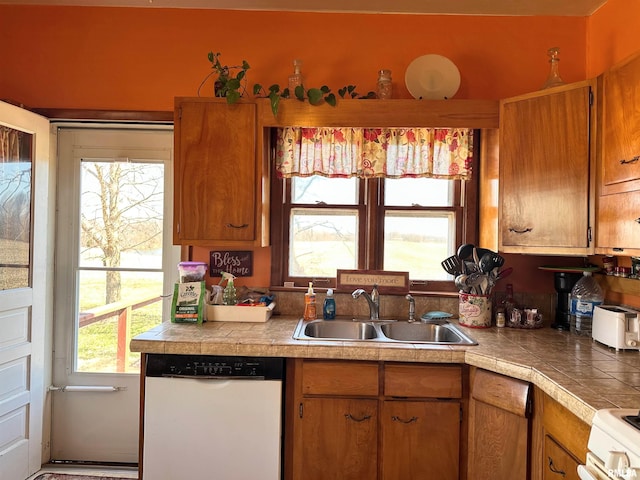 kitchen with a sink, white appliances, and brown cabinetry