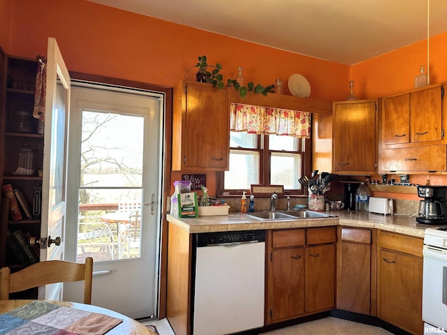 kitchen with brown cabinetry, white appliances, light countertops, and a sink