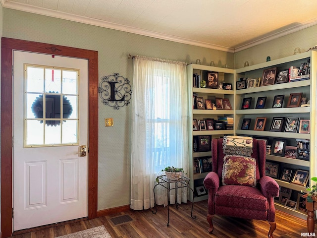 sitting room with visible vents, wood finished floors, crown molding, and wallpapered walls