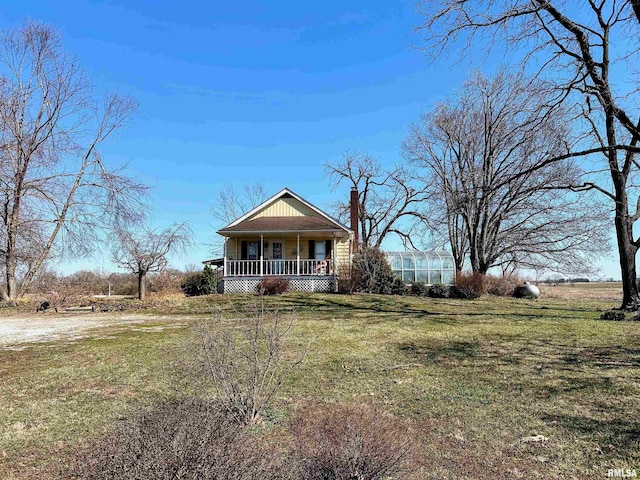 bungalow with a front yard, covered porch, and a chimney