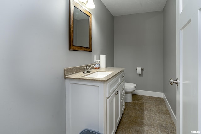 bathroom with toilet, vanity, and baseboards