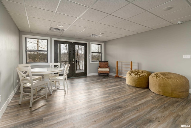 dining space with visible vents, french doors, a paneled ceiling, and wood finished floors