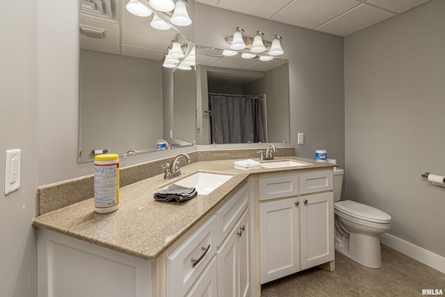 full bathroom with a sink, baseboards, a paneled ceiling, and toilet