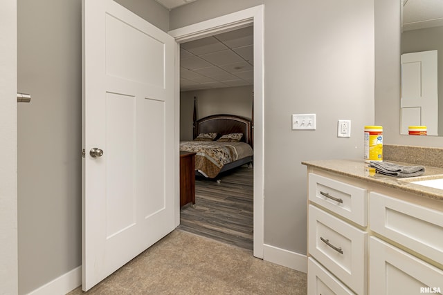 bathroom with vanity, a paneled ceiling, and baseboards