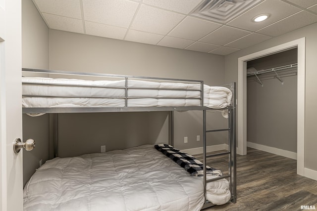 bedroom featuring a drop ceiling, visible vents, baseboards, and wood finished floors